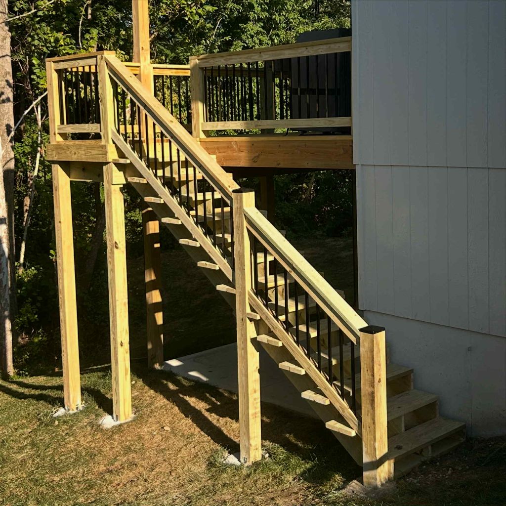 Elevated deck with black metal post railing system and integrated stairs