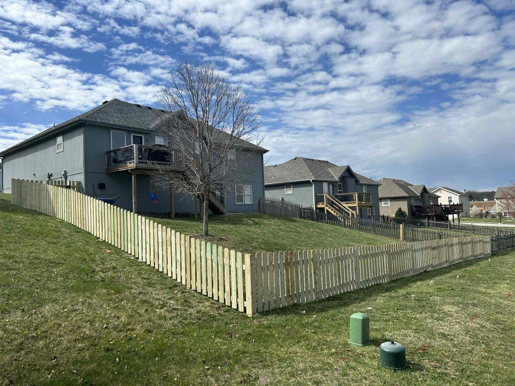 White picket fence installed on a sloped property